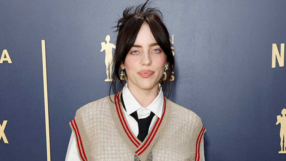 Billie Eilish at an event wearing a beige vest and black tie, amid controversy over a comment during Ireland show deemed racist