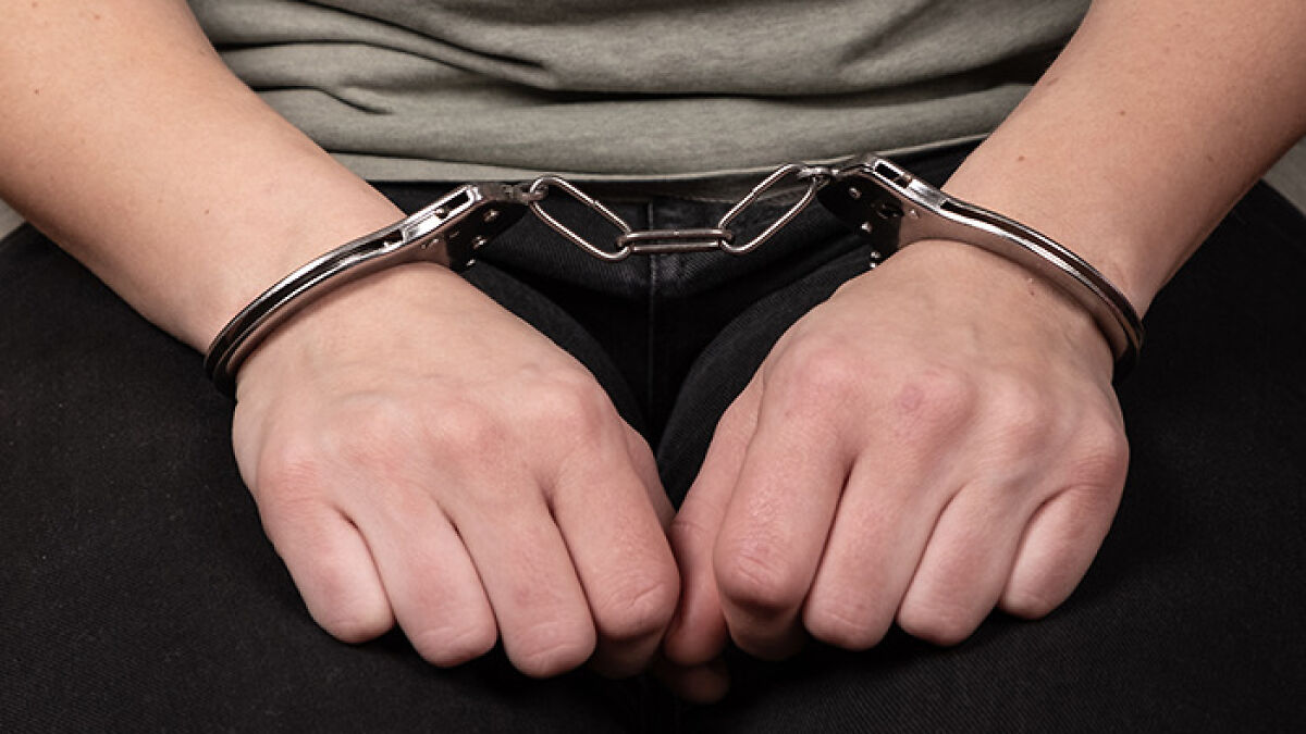 Woman's hands in handcuffs, symbolizing stalking and jail related to a neighbor after a one-night stand incident