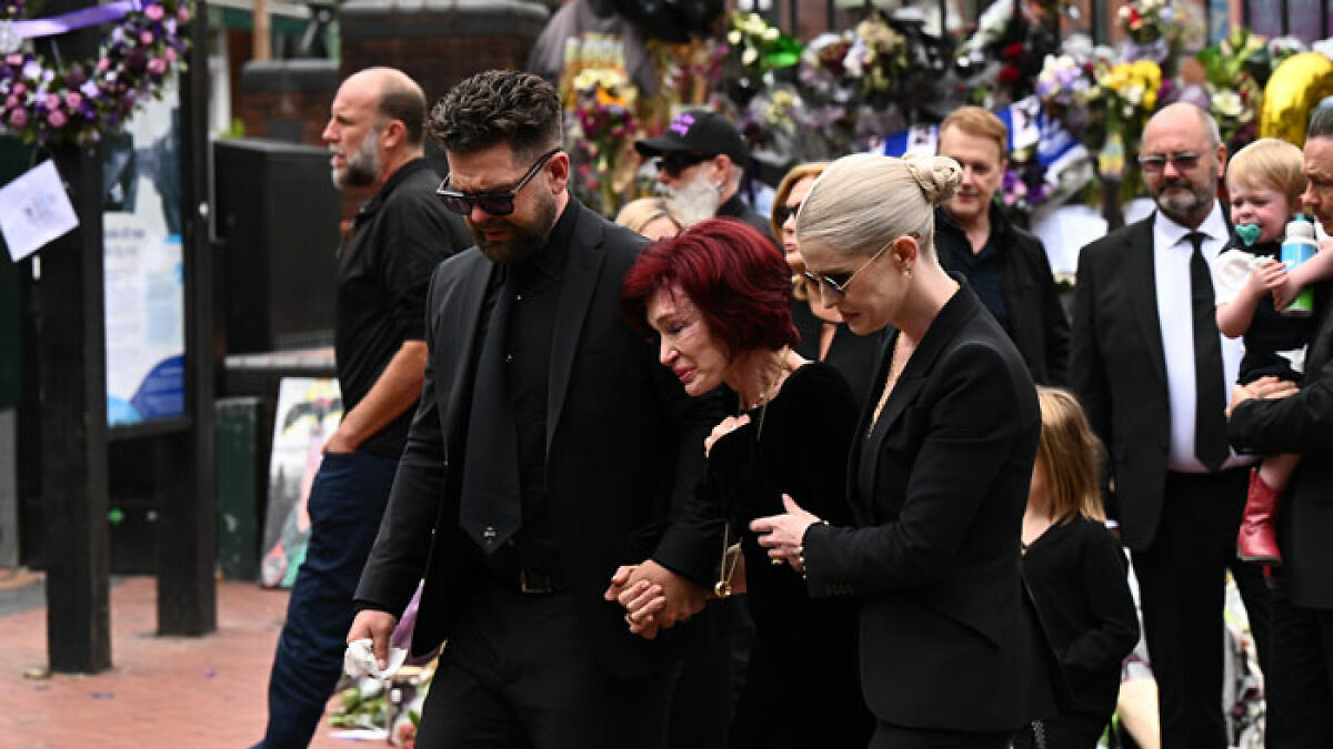 Sharon Osbourne tearfully holding hands with family at Ozzy's funeral during a heartbreaking farewell surrounded by mourners.