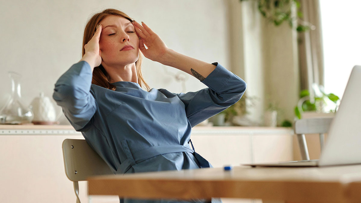 Woman at desk stressed about coworker conflict over sending GIFs in Slack affecting morale at work