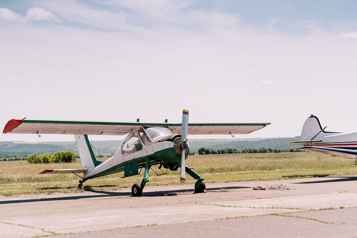 Small vintage airplane parked on runway with open cockpit on a clear day, illustrating weird first responder calls in aviation.