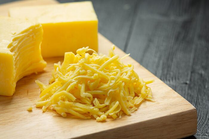 Shredded cheese and cheese blocks on a wooden cutting board, highlighting unusual calls first responders handle.