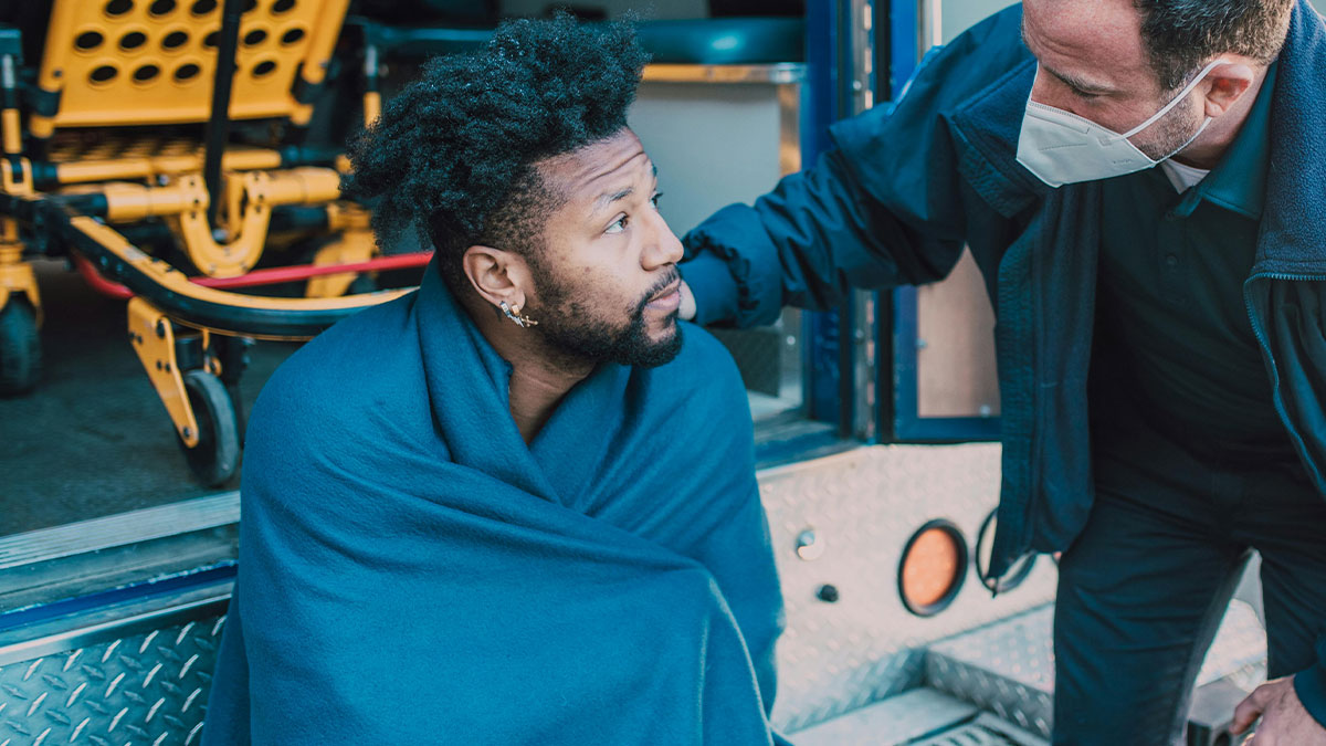First responders comforting a man wrapped in a blanket outside an ambulance during a strange emergency call.