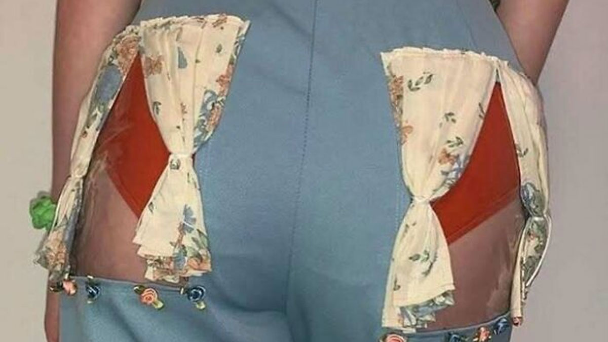 Close-up of chaotic fashion combining trash and culture with floral curtains attached to pants in a humorous style.