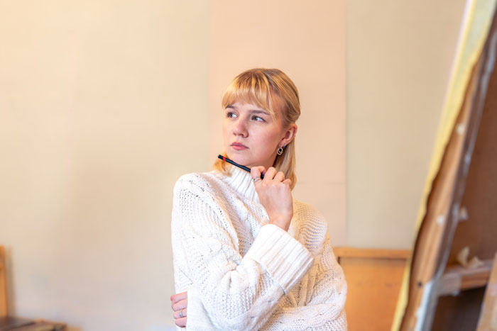 Young woman in a white sweater holding a pen, looking thoughtful about dad and stepmom family issues. Young woman in a white sweater holding a pen, looking thoughtful about dad and stepmom family issues.