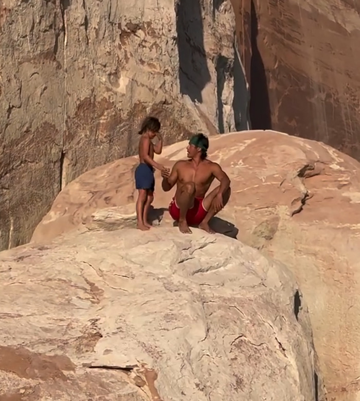 Man and young boy on rocky cliff edge during an outdoor moment related to dad teaching son to face fears controversy. Man and young boy on rocky cliff edge during an outdoor moment related to dad teaching son to face fears controversy.