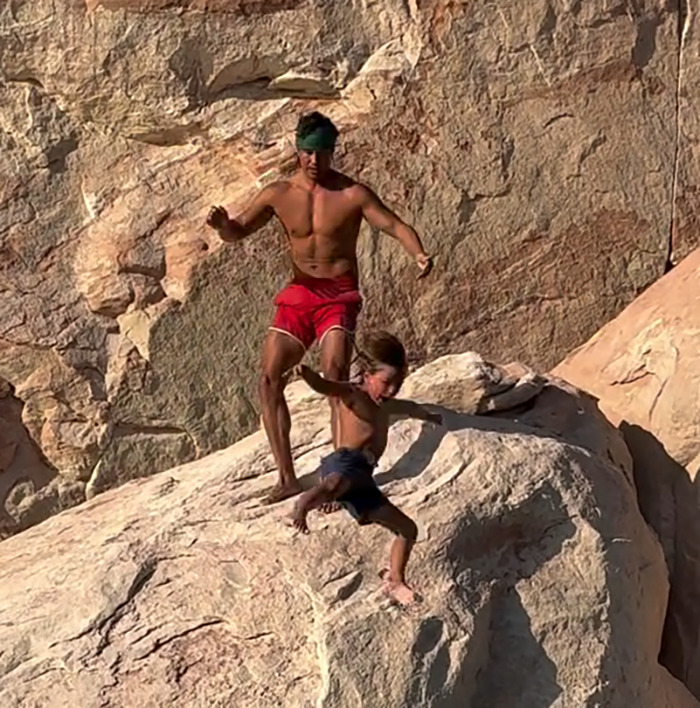 Man in red shorts throwing 7-year-old son off cliff to teach him to face his fears, sparking public outrage. Man in red shorts throwing 7-year-old son off cliff to teach him to face his fears, sparking public outrage.
