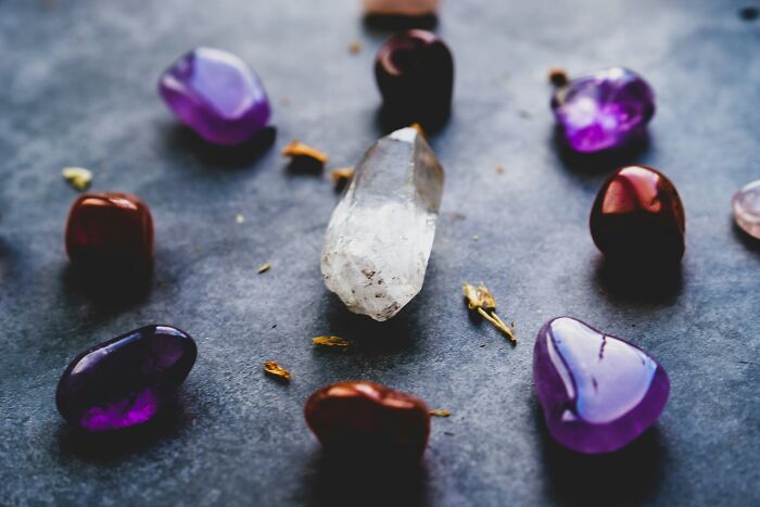 Clear quartz and amethyst crystals arranged in a circle on a dark surface, representing common bizarre beliefs.