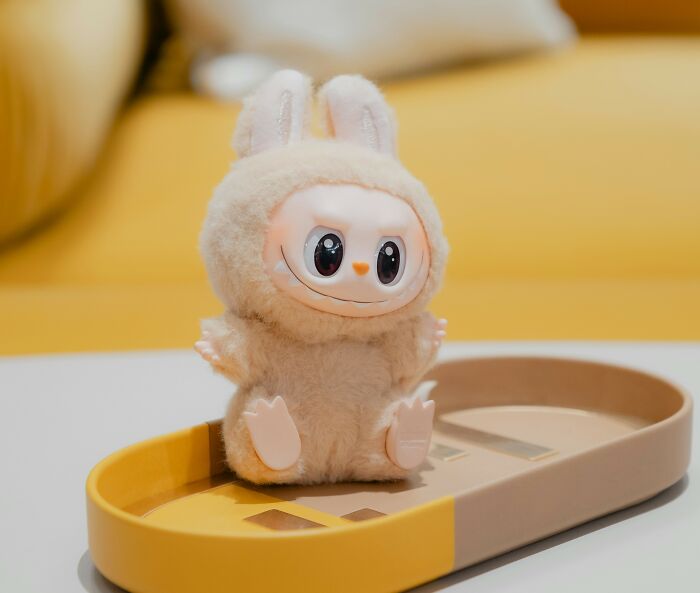 Plush toy with bunny ears sitting on a yellow and beige tray, representing trends contributing to overconsumption concerns.