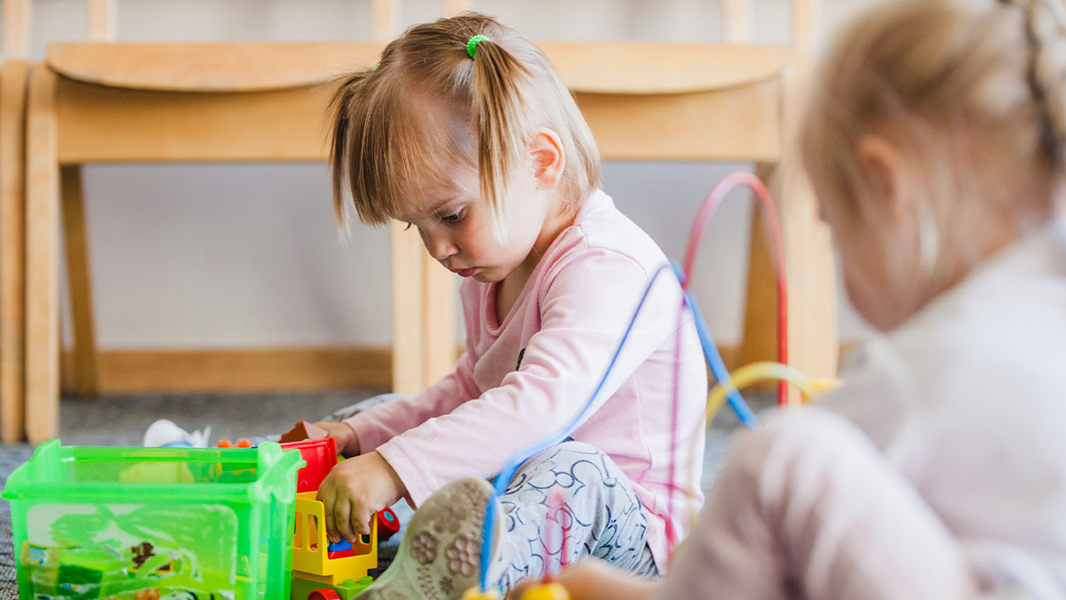 Two young children playing with toys indoors depicting daycare and custody weeks situation.