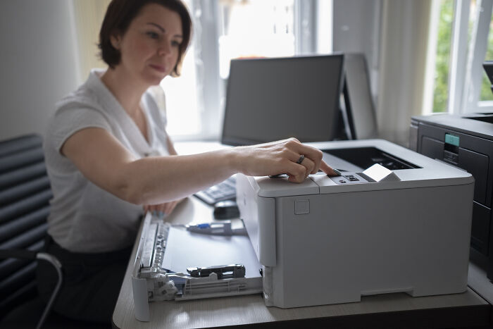Woman using a printer in a modern office, illustrating deaf people revealing surprisingly silent things assumed noisy.