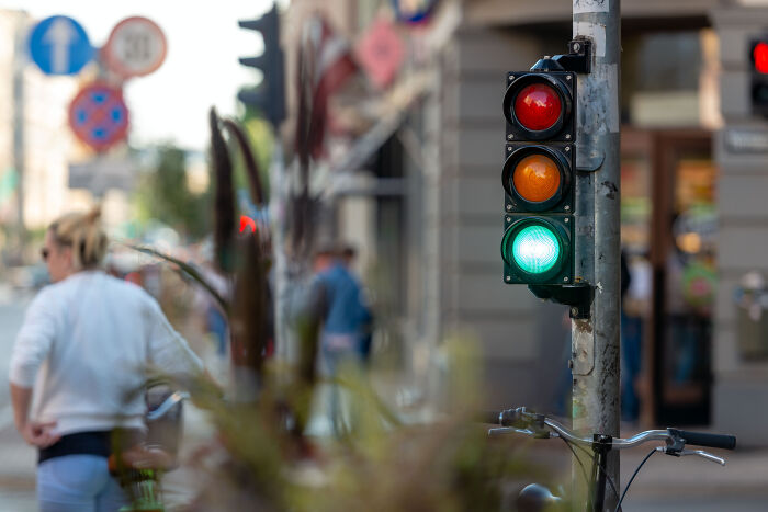 Traffic light glowing green at a busy urban street with blurred pedestrians, illustrating silent experiences for deaf people.