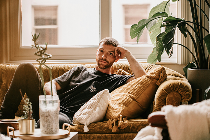 Man looking stumped while sitting on a couch, reflecting on generational trauma and family apology demands.