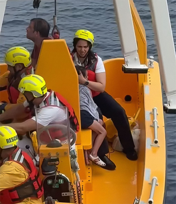 Rescue team wearing helmets and life vests comforting a girl during Disney cruise ship fall incident on a rescue boat. Rescue team wearing helmets and life vests comforting a girl during Disney cruise ship fall incident on a rescue boat.