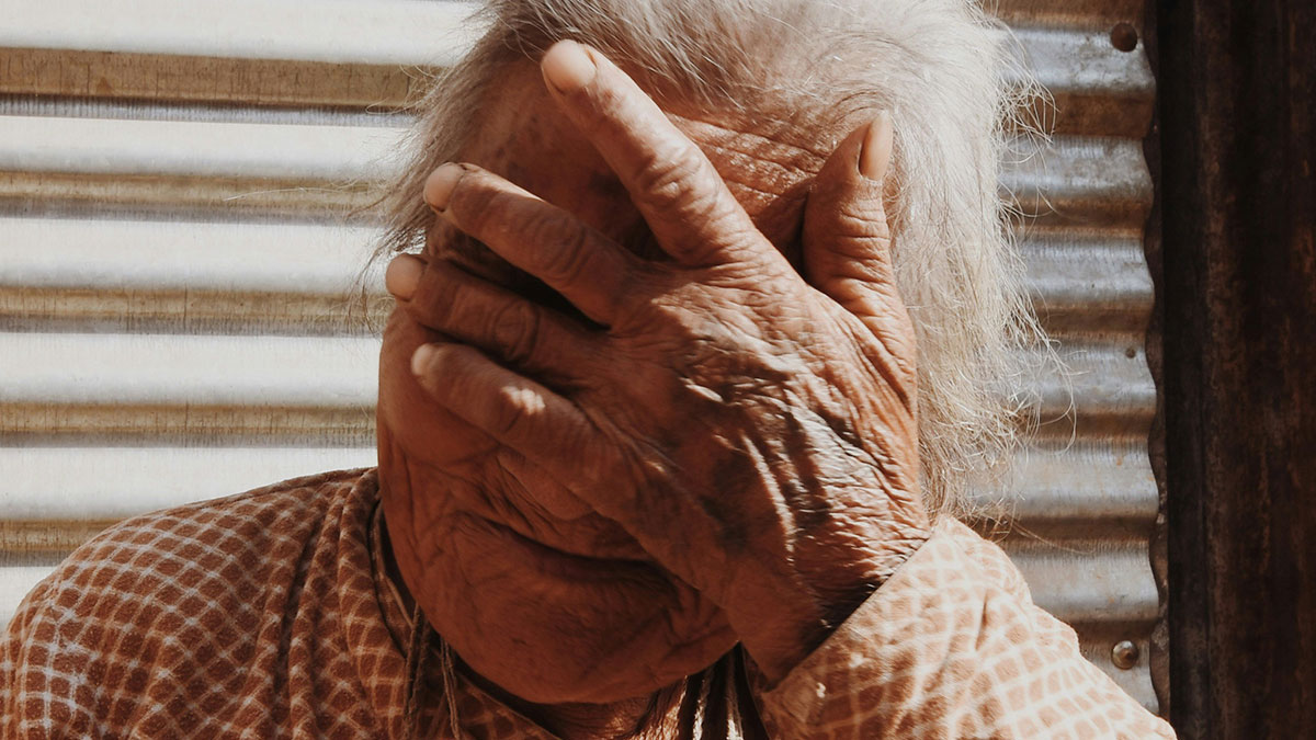 Elderly person covering face in distress, illustrating patients delayed help with shocking health consequences.
