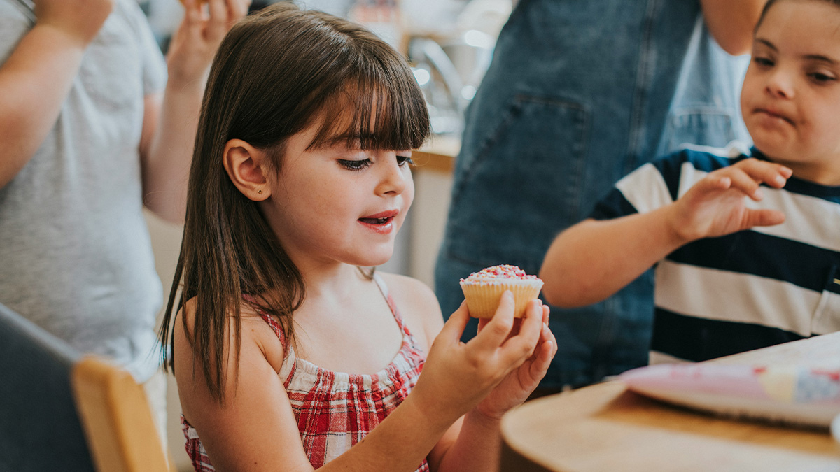 Young girl holding cupcake with sprinkles, kids enjoying a sweet moment while learning from mistakes and doing things wrong.