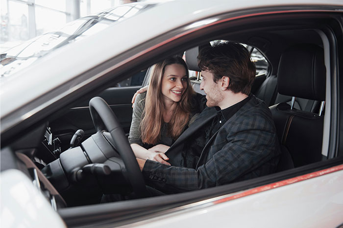 A young couple sitting inside a car, smiling and sharing a moment, illustrating times people decided to stop helping.