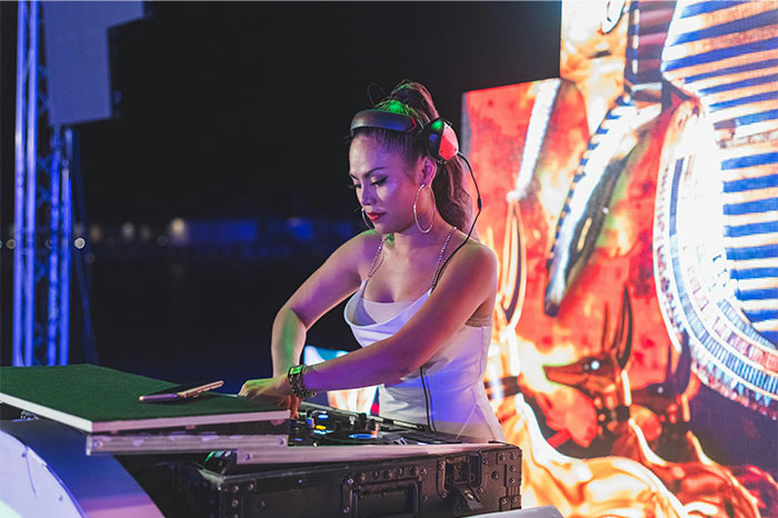 Woman DJ wearing headphones, focused on mixing music at an outdoor event, illustrating times people stopped helping others.