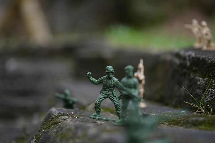 Green plastic toy soldiers arranged on mossy rocks illustrating crazy but real historical events realistic in movies.