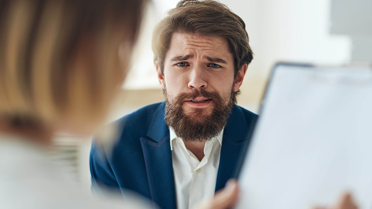 Man upset during job interview, expressing frustration over recruiter judging work ethics with a question about Grand Canyon