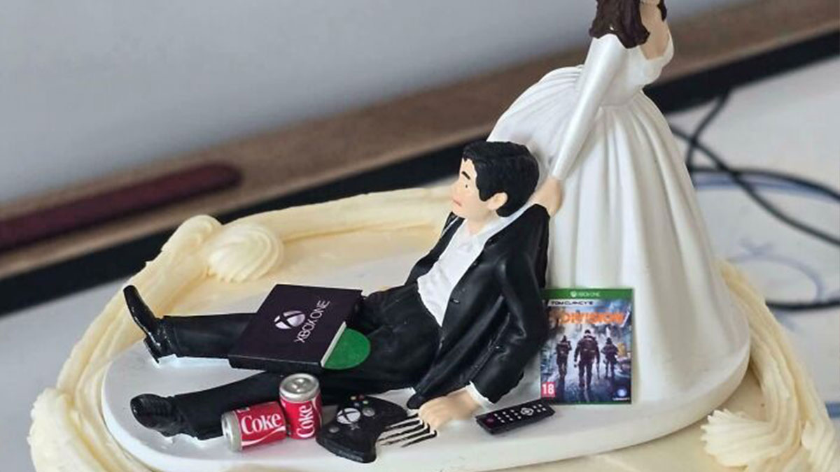 Groom figurine lying down with video games and soda on a wedding cake topper showing entitlement behavior.