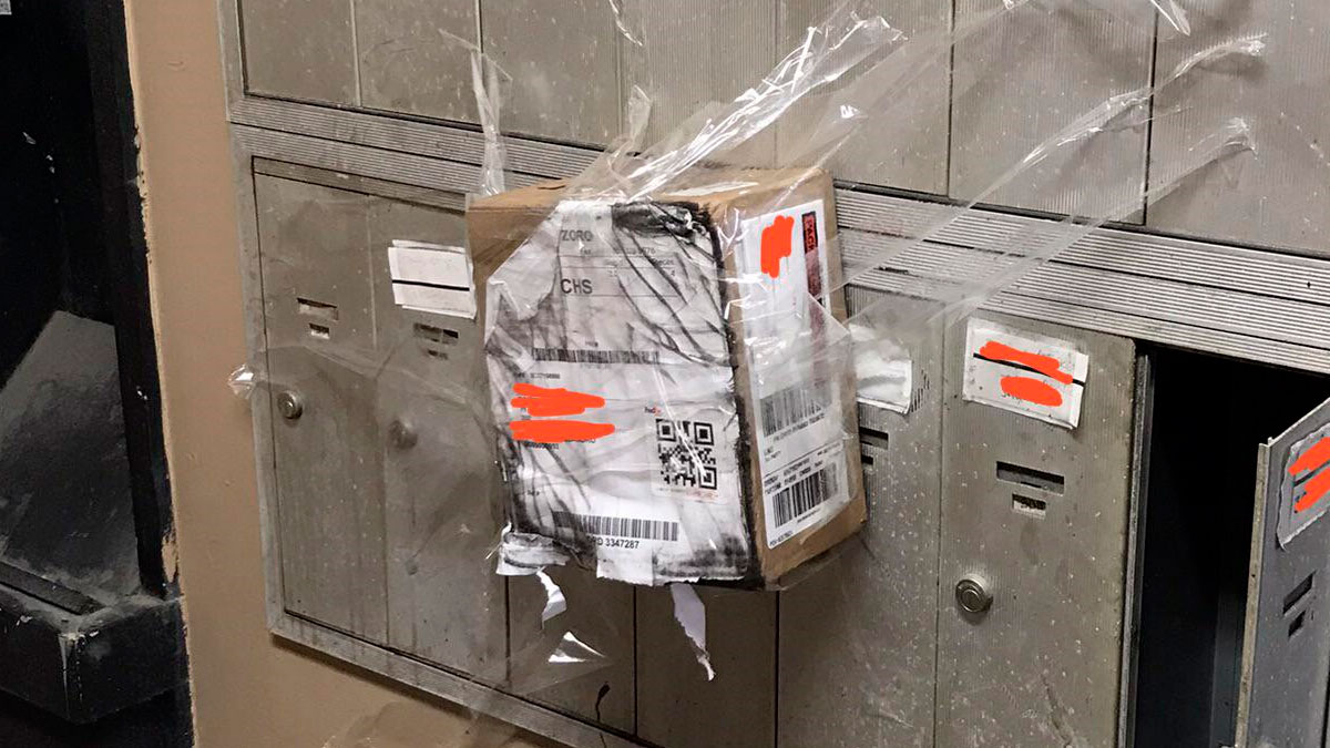 Package taped awkwardly outside a mailbox, illustrating delivery mishaps and unfortunate package handling incidents.