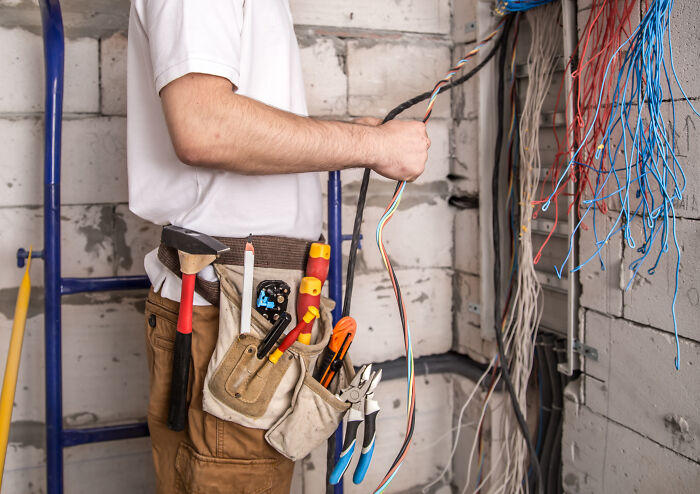 Escape room employees handling complex wiring and tools while setting up an immersive game environment.