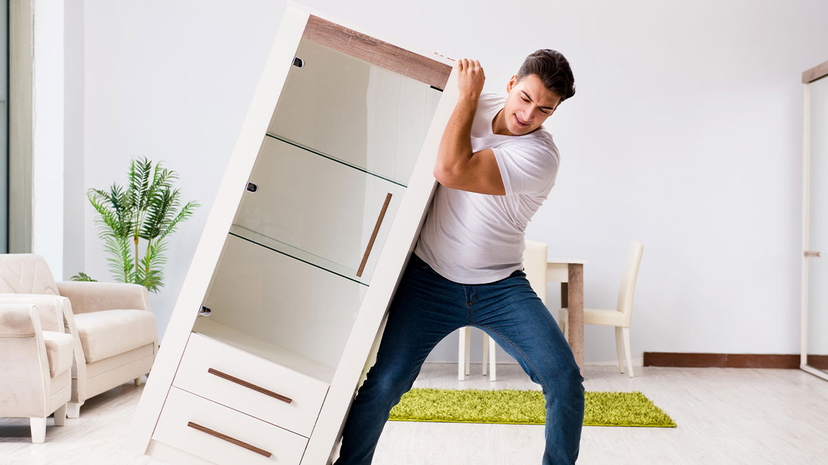 Man struggling to move large cabinet indoors, illustrating weird and wacky escape room exit attempts.