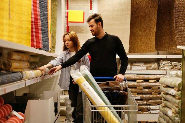 A young man and woman calmly discussing fabric choices while shopping in a textile store aisle.