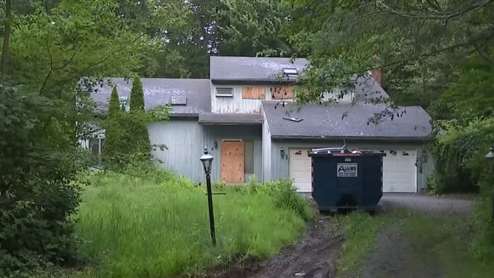 Overgrown yard and boarded-up hoarder house where police discovered skeletal remains beneath trash inside. Overgrown yard and boarded-up hoarder house where police discovered skeletal remains beneath trash inside.