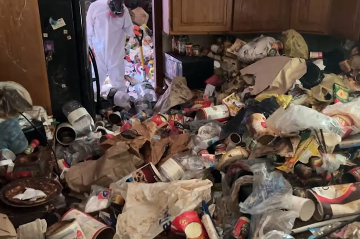 Police officer in protective gear investigates skeletal remains amid hoarder's trash-filled house of horrors. Police officer in protective gear investigates skeletal remains amid hoarder's trash-filled house of horrors.