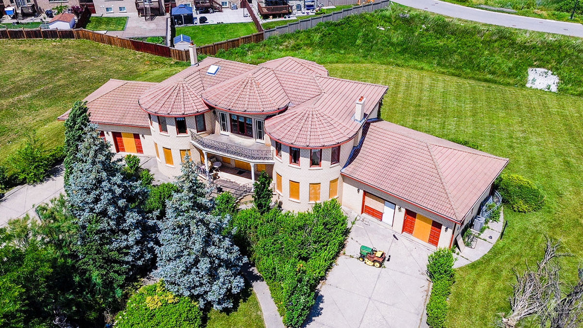 Abandoned luxury mansion with boarded windows surrounded by greenery, showcasing eerie urban exploration of a $12 million time capsule.