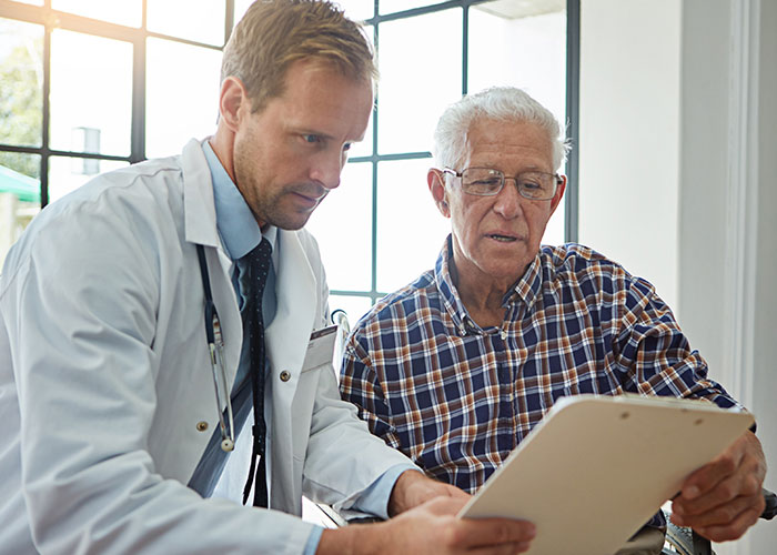 Doctor explaining medical document to elderly man in a plaid shirt, discussing organ donation and patient care options. Doctor explaining medical document to elderly man in a plaid shirt, discussing organ donation and patient care options.