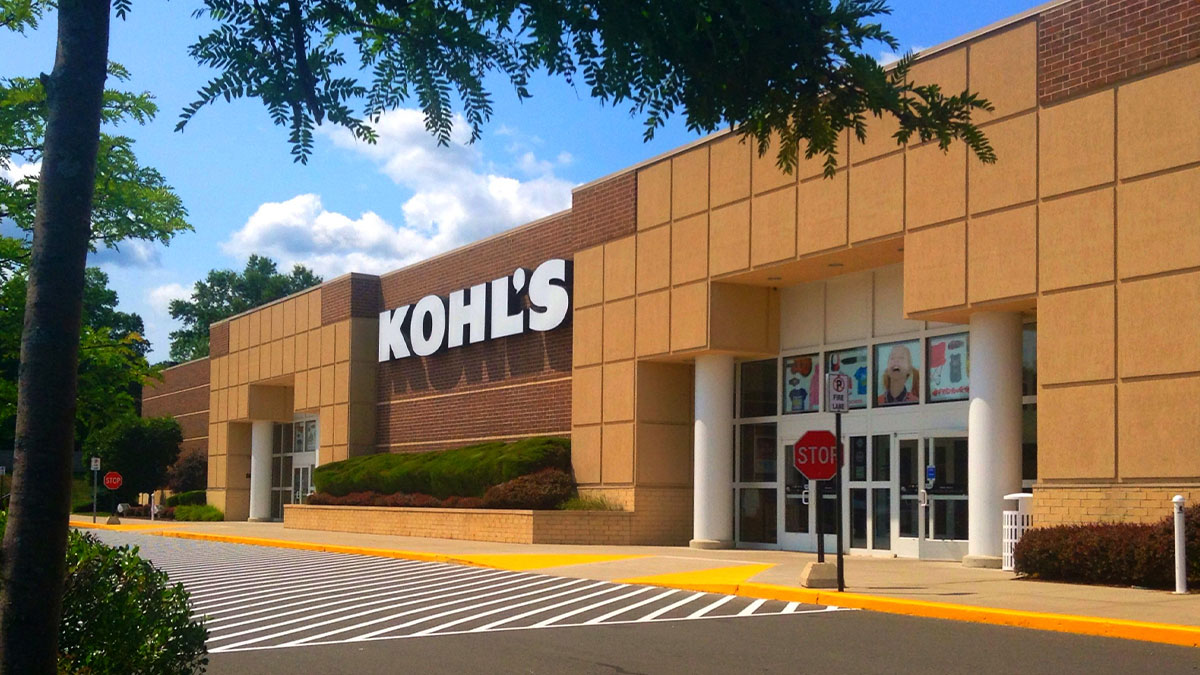 Kohl's store exterior on a sunny day with empty parking lot and visible stop signs, illustrating a job experience setting.