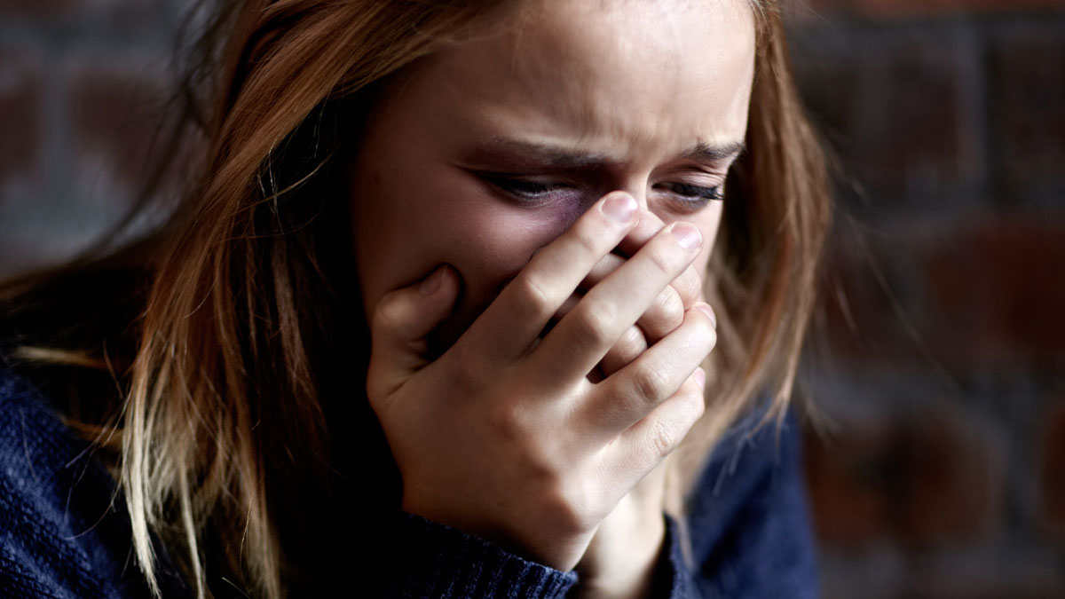 Woman crying with hand covering mouth, emotional reaction to discovering storage unit contents left by dad in will
