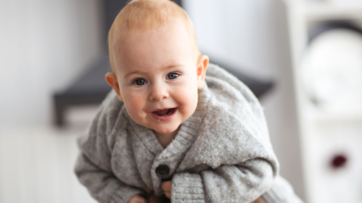 Smiling baby in a cozy gray sweater representing single mom challenges and babysitting expectations from a bestie.