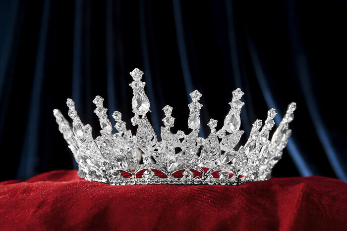 Silver jeweled crown resting on red velvet, symbolizing Gen Z's unique and outlandish compliments like queen and GOAT.