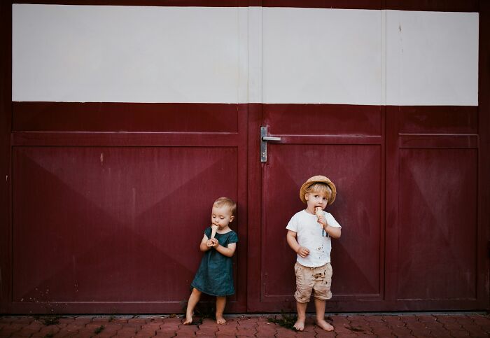 Two young children eating ice cream while standing barefoot in front of a large red door, people share reasons not divorced.