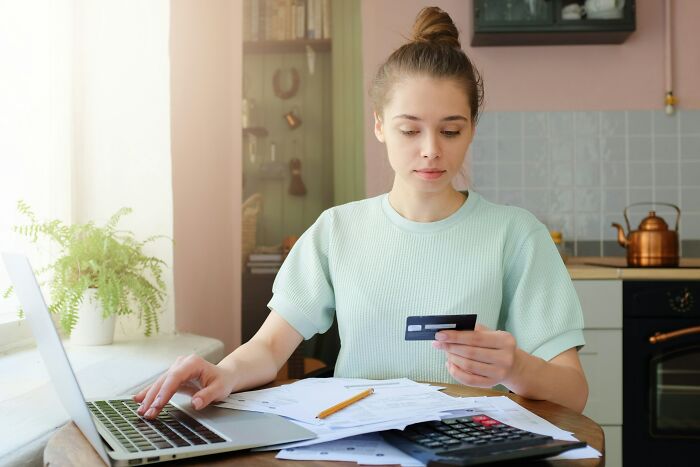 Young woman managing finances on laptop and calculator, illustrating people share reasons not divorced concept.
