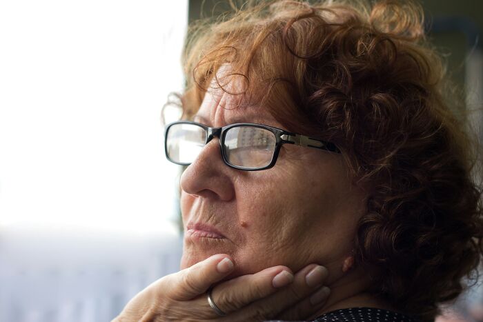 Older woman wearing glasses, deep in thought, reflecting on reasons people share for not divorced.