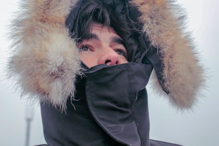 Person bundled in heavy winter clothing with fur-lined hood, illustrating bizarre beliefs about cold weather myths.