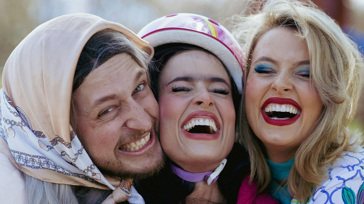 Three friends happily smiling together outdoors, showcasing genuine connection and green flags in relationships.