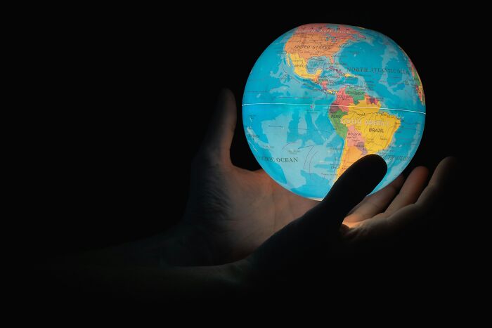 Hands gently holding an illuminated globe in darkness, symbolizing debunked lies people believe about the world.