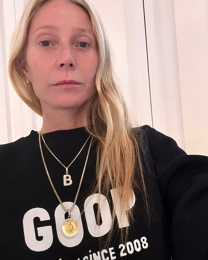 Gwyneth Paltrow wearing black GOOP sweatshirt and gold necklaces, showing casual style in a close-up selfie. Gwyneth Paltrow wearing black GOOP sweatshirt and gold necklaces, showing casual style in a close-up selfie.