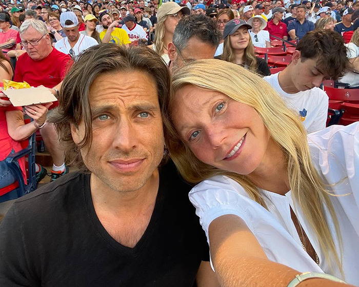 Gwyneth Paltrow smiling with a man at a crowded outdoor event, fans react to her trash-handling skills in cooking video. Gwyneth Paltrow smiling with a man at a crowded outdoor event, fans react to her trash-handling skills in cooking video.