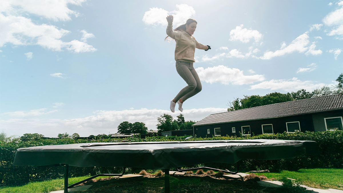 Person jumping on trampoline outdoors with sky and house in background illustrating habits and life quality decisions