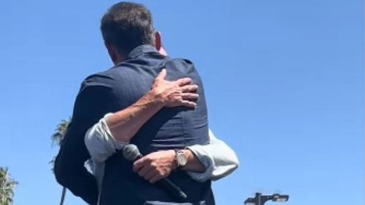 Two Harry Potter stars embracing during a surprise reunion outdoors against a clear blue sky.