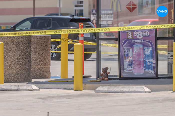 Teddy bear covered in apparent human remains sits outside convenience store behind yellow police tape near parking area. Teddy bear covered in apparent human remains sits outside convenience store behind yellow police tape near parking area.