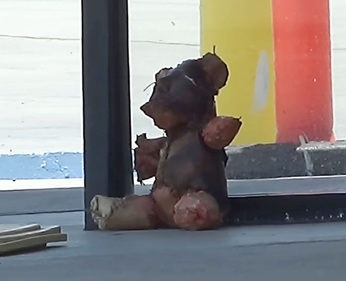 Worn teddy bear covered in apparent human remains sitting outside a convenience store on a concrete surface. Worn teddy bear covered in apparent human remains sitting outside a convenience store on a concrete surface.