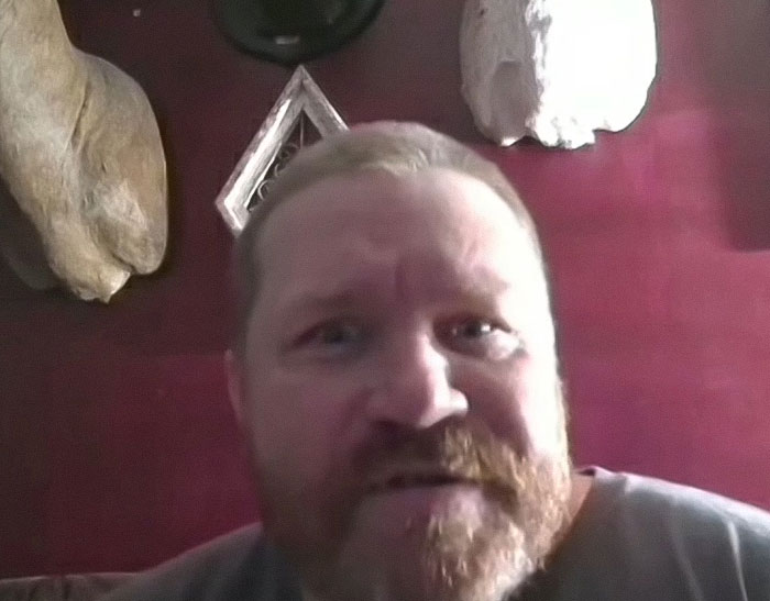 Man with red beard in a dim room, discussing a horrifying teddy bear covered in apparent human remains. Man with red beard in a dim room, discussing a horrifying teddy bear covered in apparent human remains.